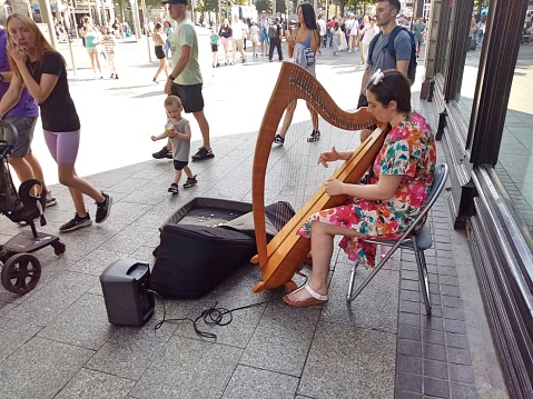 9th September 2023, Dublin, Ireland.  Woman busker playing the harp on O'Connell Street, Dublin city centre.
