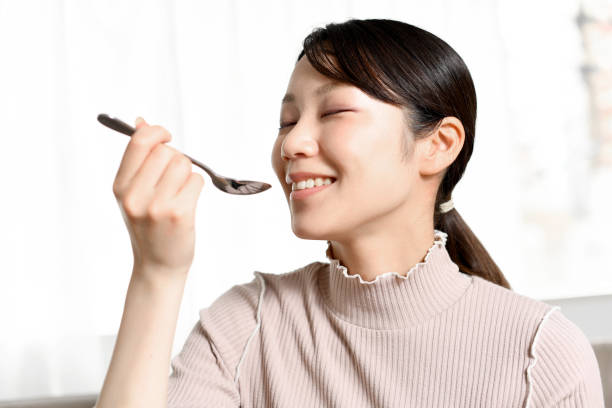 Young dark-haired Asian woman eating with a spoon