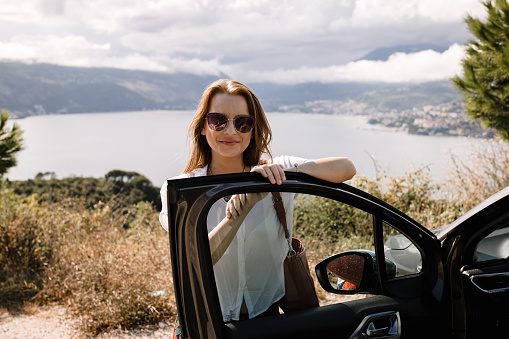 Portrait of a smiling young woman relaxing and enjoying a summer vacation and a road trip at the seaside in Montenegro on a sunny day