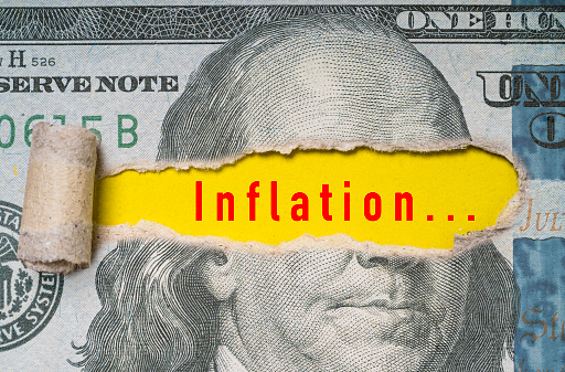 USD dollar banknote was torn at Benjamin Franklin 's eye with inflation wording for United of America increasing interest rating to stop and reduce increase of price of goods concept.
