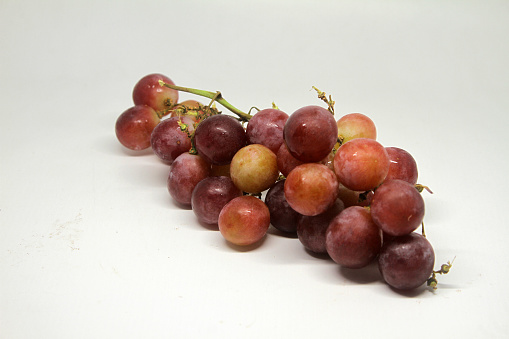 Ripe red grape. Pink bunch with leaves isolated on white. With clipping path. Full depth of field.