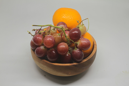 grapes and oranges on a wooden bowl