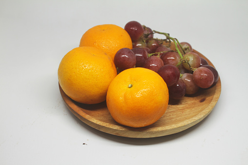 grapes and oranges on a wooden plate