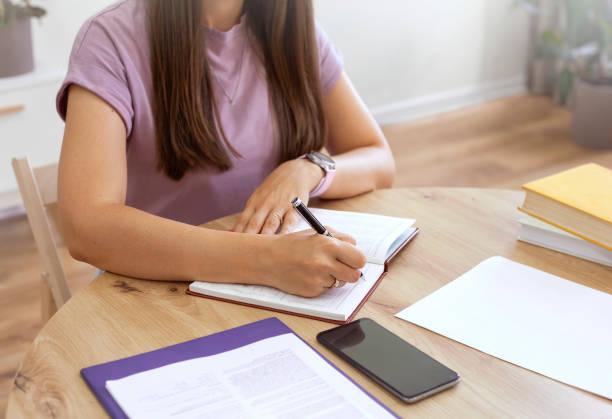 istock Close-up of woman writing in notepad while sitting at table 1678271182