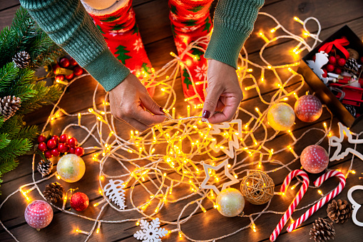 High angle view of unrecognizable woman untangling Christmas string lights for Holidays. High resolution 42Mp studio digital capture taken with SONY A7rII and Canon EF 70-200mm f/2.8L IS II USM Telephoto Zoom Lens