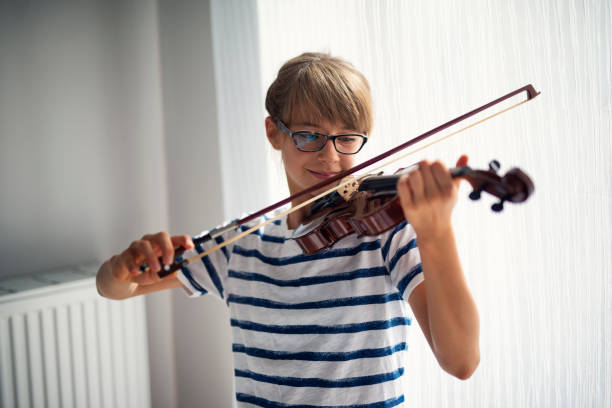 istock Happy little girl practicing violin at home 1678287586