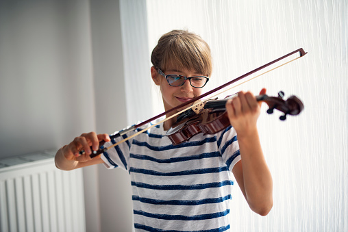 Little girl aged 10 is practicing violin at home.\nShot with Nikon D800