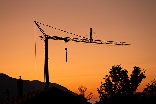 Construction machinery - silhouette of a construction crane with sunset in the background. August evening in Upper Bavaria, Germany.