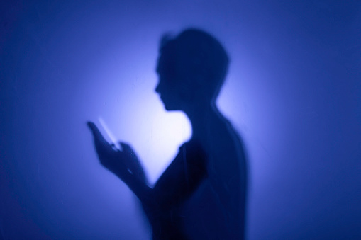 Silhouette of woman holding a smartphone.