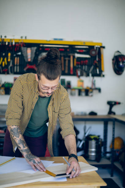 istock Young craftsman in his workshop measuring a wooden plank 1678306575