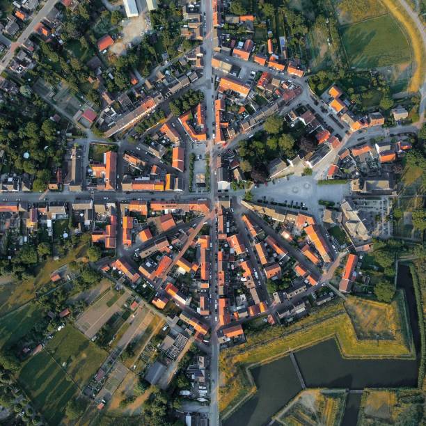istock a city with a clock tower and a river next to a green field 1678307700