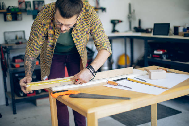 istock Young craftsman in his workshop measuring a wooden plank 1678311708