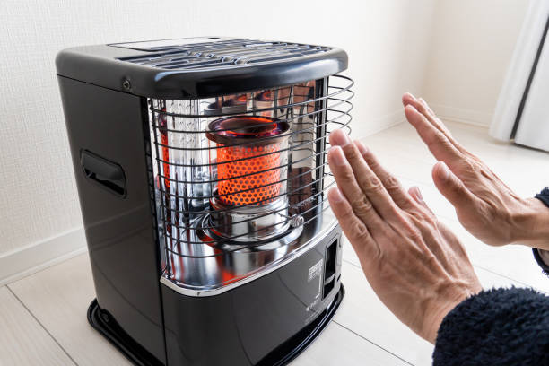 A man's hands are warmed by a heater