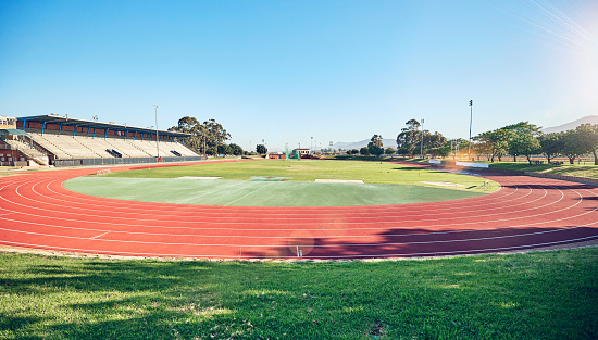 Sport, fitness and stadium track for running, outdoor and exercise landscape, blue sky and grass. Active, workout motivation and run for healthy life and sports view sun flare with cardio.