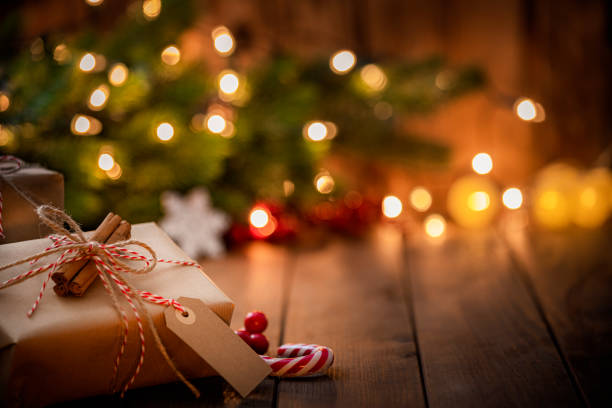 brown christmas gift box with a blank tag on rustic wooden table. - noel bayramı stok fotoğraflar ve resimler