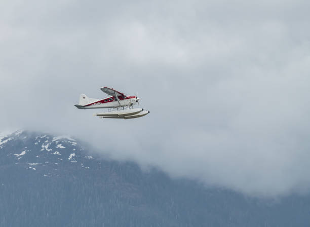 DeHavilland DHC-2 Float Plane Flying low past cloud covered mountains Alaska, USA