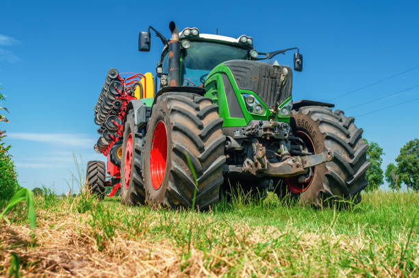 istock Bright tractor with a field drill. Low angle view through grass to equipment. Agricultural landscape 1678343921