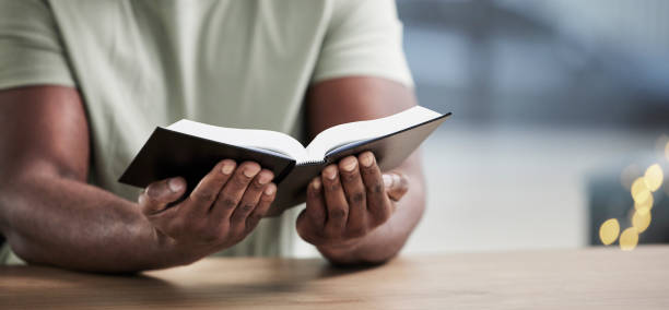 istock Bible, reading and man hands with book learning for religion study at home for worship and spiritual support. Faith, christian knowledge and person with gratitude, scripture education and guidance 1678368667