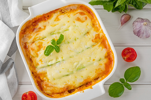 Delicious zucchini lasagna with sauce bolognese in a baking dish on a white wooden bachground. Healthy food. Top view. Selective focus