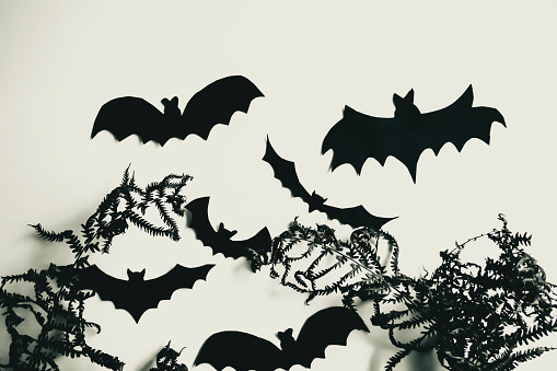 Bats in dry grass. In a dried fern, black bats made of paper. Halloween crafts - home decorations.