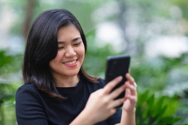 istock Smiling young woman using her mobile phone outdoors in the park 1678409054