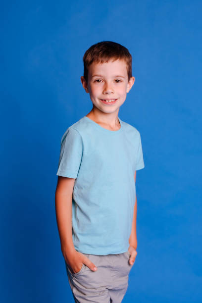 istock happy smiling school boy in blue mockup T-shirt looking at camera over light blue studio background 1678421490