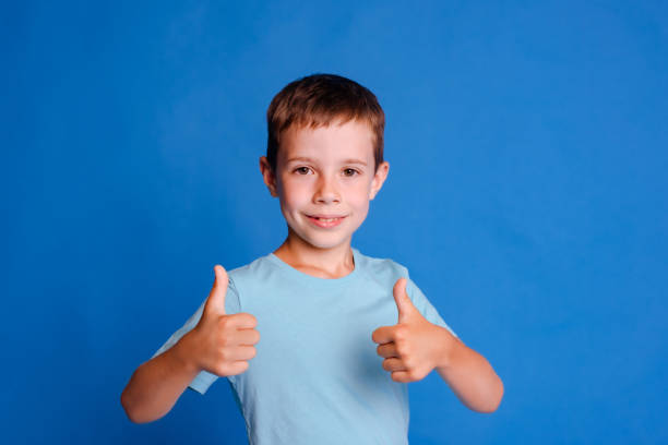 istock headshot boy show thumb up gesture in blue T-shirt looking at camera over light blue studio background 1678421494