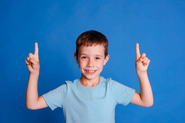 istock headshot boy point index fingers up to free copy space on light blue studio background 1678421515