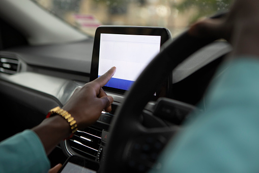 Hands setting satellite navigation on a digital before starting a car journey