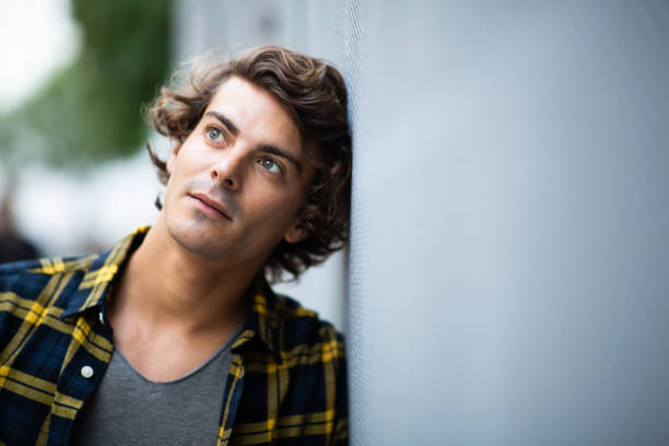 istock Thoughtful young man leaning against gray wall 1678479512