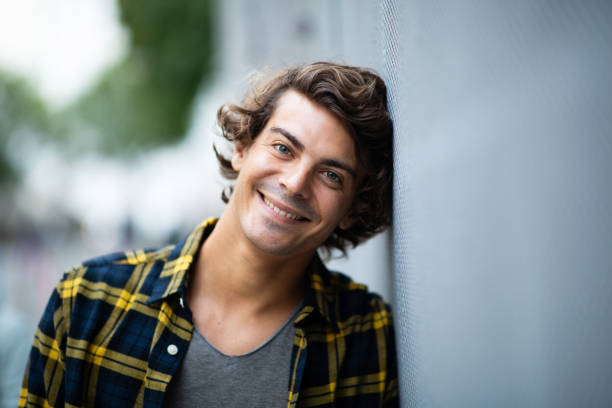 istock Good looking young guy leaning against gray wall and smiling 1678479517