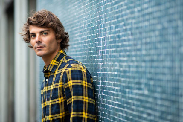 istock Handsome young man leaning against gray wall 1678480081