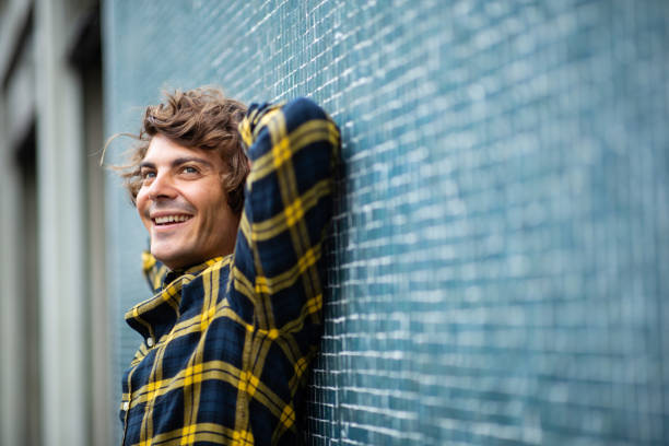 istock Cheerful young man leaning against gray wall with hands behind head 1678480613