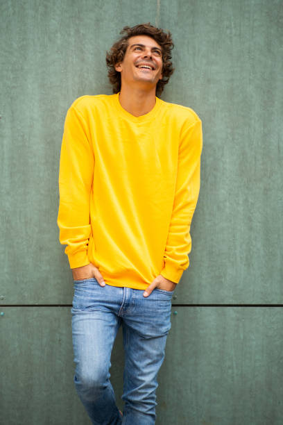 istock Smiling handsome young man with hands in pockets leaning against green wall 1678481709