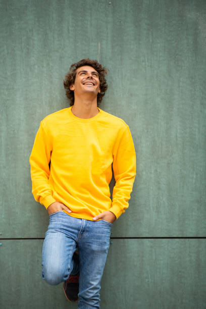 istock Handsome young guy with hands in pockets leaning against green wall 1678482828