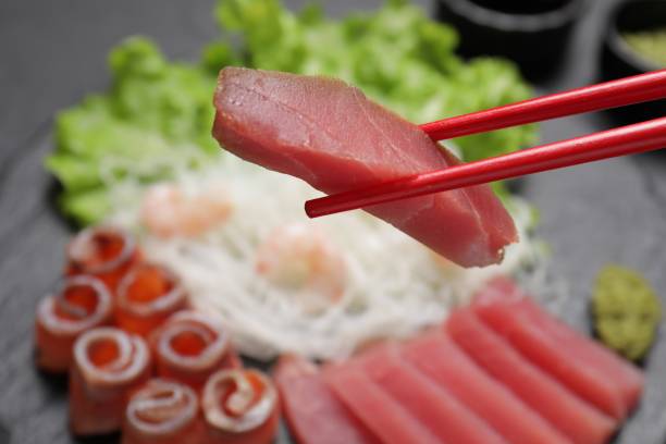 istock Chopsticks with tasty sashimi (piece of fresh raw tuna) against blurred background, closeup 1678492677