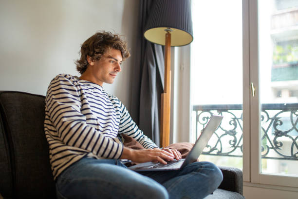 istock Young man relaxing on sofa using laptop at home 1678497738