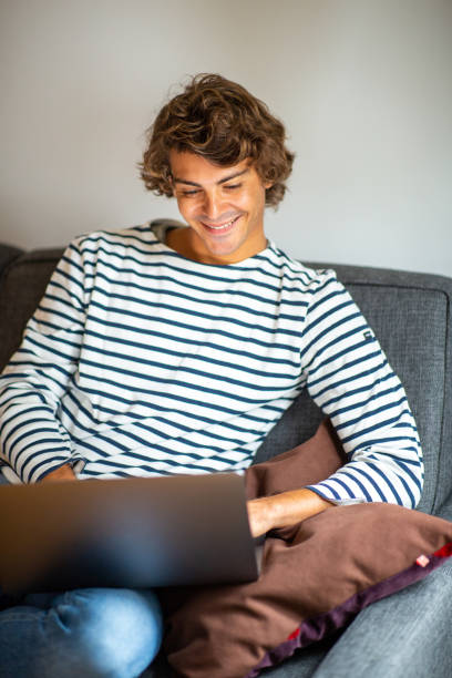 istock Smiling young man relaxing at home working on laptop 1678497743