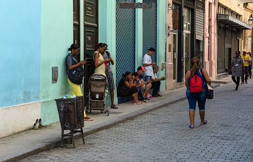Havana, Cuba, November 20, 2017: People with their cell phones use a hotspot to receive internet in downtown Havana.