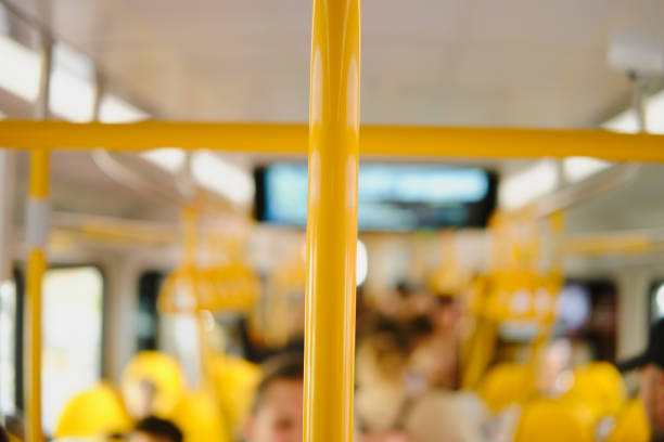 Blurred image of a yellow train with passengers in the background.