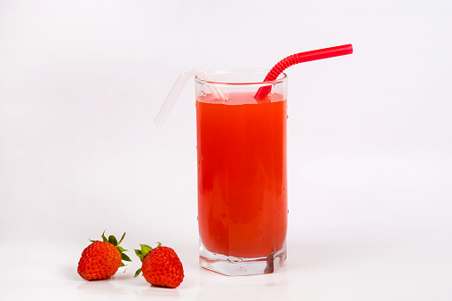 Strawberry juice in a glass with a straw on a white background. Strawberry smoothie. Milk strawberry cocktail. Cold summer drink