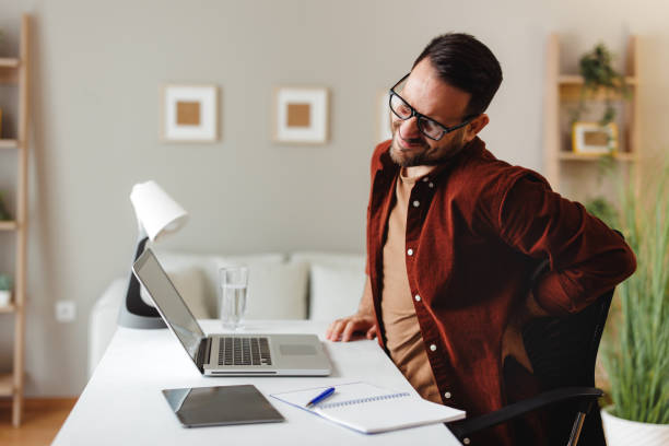 istock Young man has back pain while working in the office at a desk 1678579647