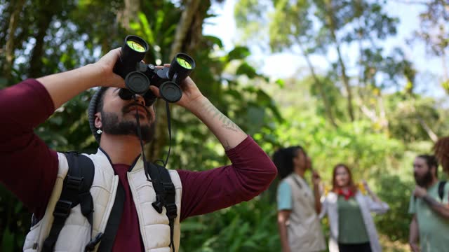 Portrait of a young man using binoculars during hiking on forest