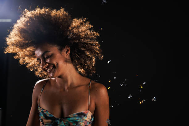 istock Shaking gold colored confetti out of her hair while dancing 1678647183