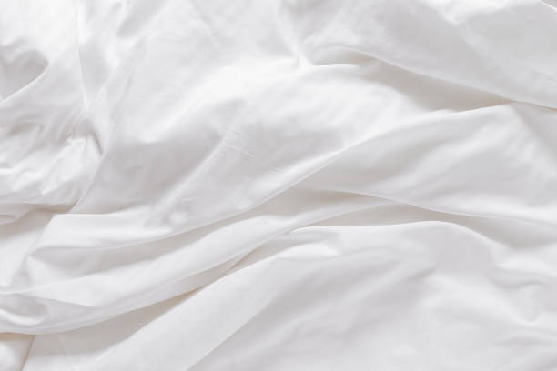 istock White fabric texture background, wavy cloth. Crease bedclothes fragment as background, Crumpled sheet of Morning bed. White bed linen as minimalistic backdrop. Top view aesthetic surface 1678662309