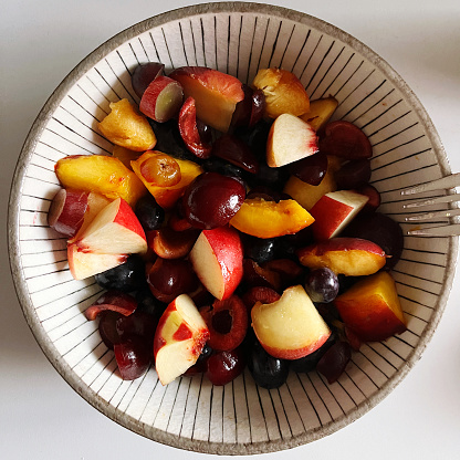 Obstsalat aus Pfirsich, Apfel, Kirsche und Trauben in einem japanischen Teller.