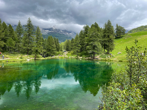 Clouds reflected in a pristine green alpine lake with Matterhorn in the mist, Aosta Valley, Italy