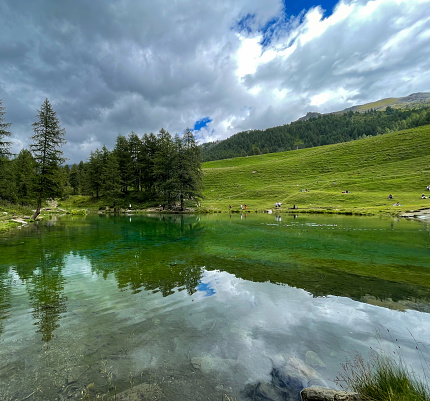 Cloudy sky reflected in the transparent green waters of Lac Bleu at feet of Matterhorn mountain, Aosta Valley, Italy