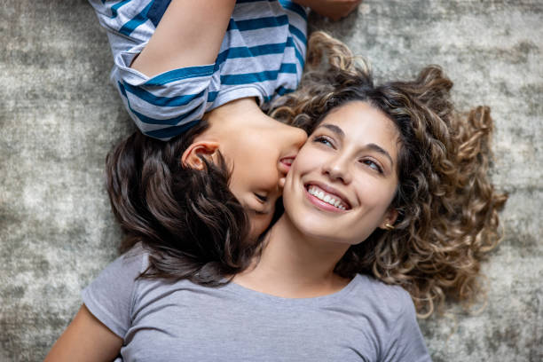 istock Loving son kissing her mother while lying on the floor 1678740264