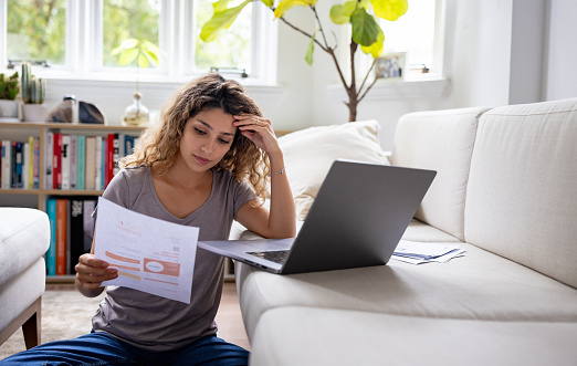 Woman looking worried about her home finances while reading her bank statement - bankruptcy concepts